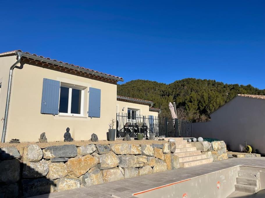 a house with a stone wall and a building at Le Mas No'Stelou in Pierrelongue