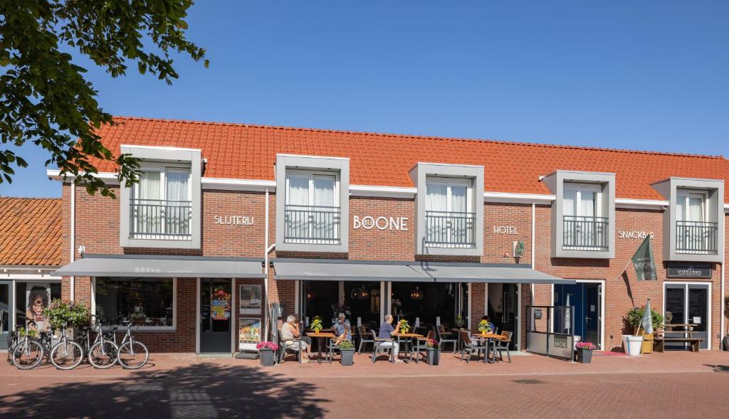 a building with people sitting at tables in front of it at Hotel bij Boone in Meliskerke