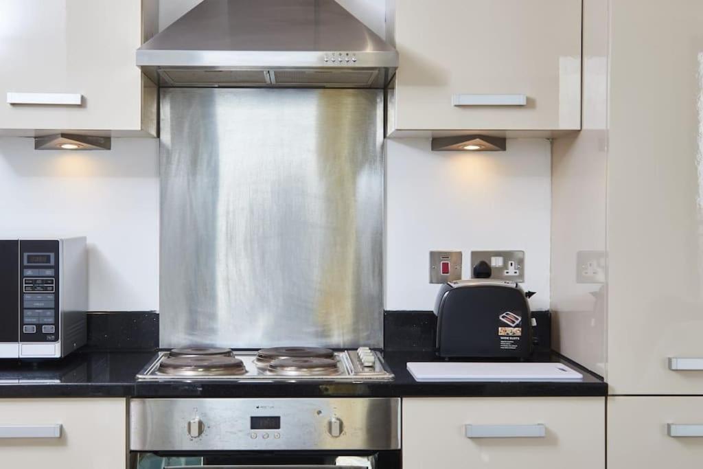 a kitchen with a stove and a microwave at Yorksha Luxury Apartments Leeds in Leeds