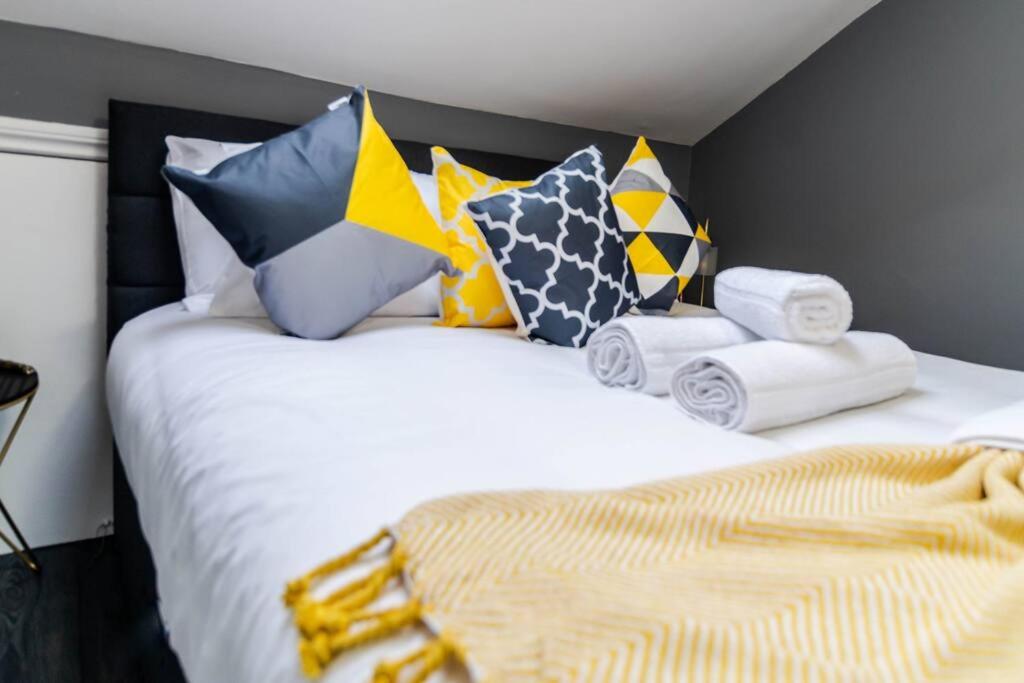 Inviting 1BRStudio, PrivateBth l CentralLondon Gem في لندن: غرفة نوم مع سرير أبيض مع وسائد ملونة