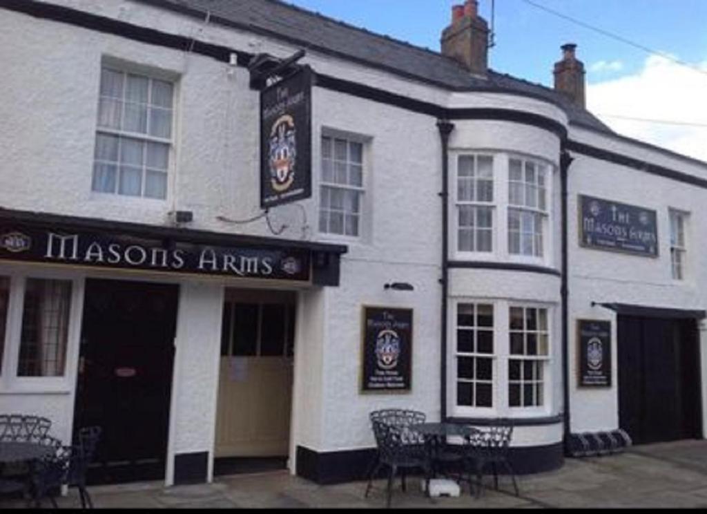 a white building with chairs in front of it at Mason's Arms in Norham