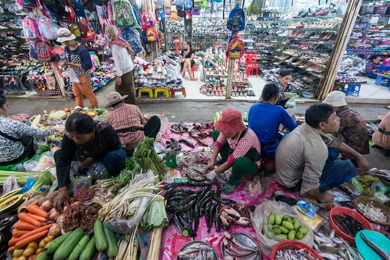 un gruppo di persone che siedono intorno a un mercato con verdure di The Village Homestay a Siem Reap