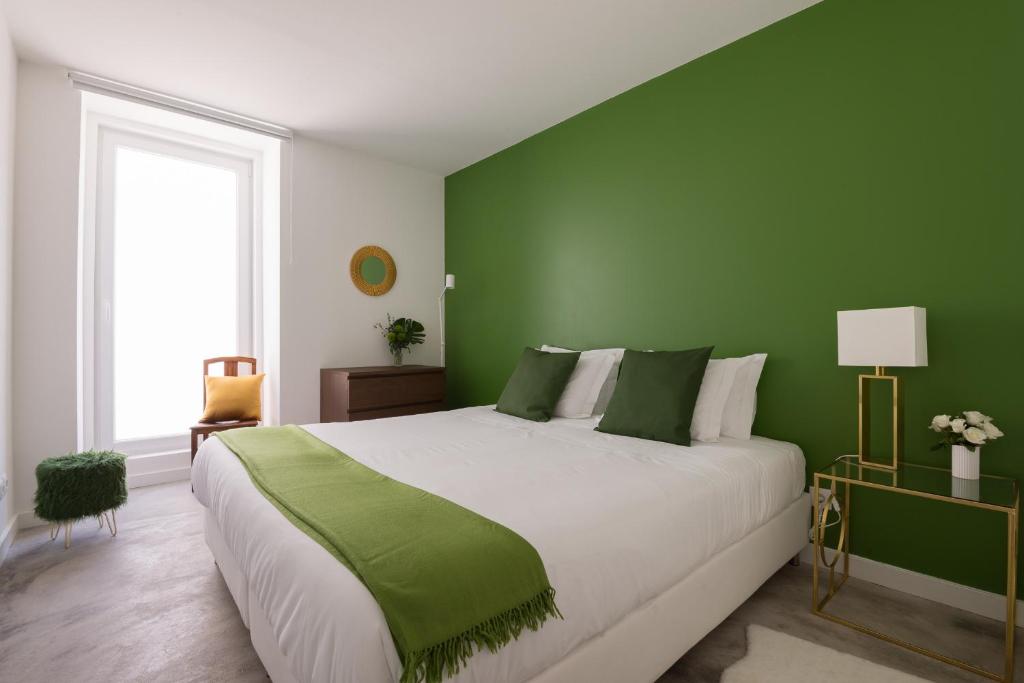 a bedroom with a large bed with green walls at CASASUPERTUBOS® Apart 9-14 in Peniche