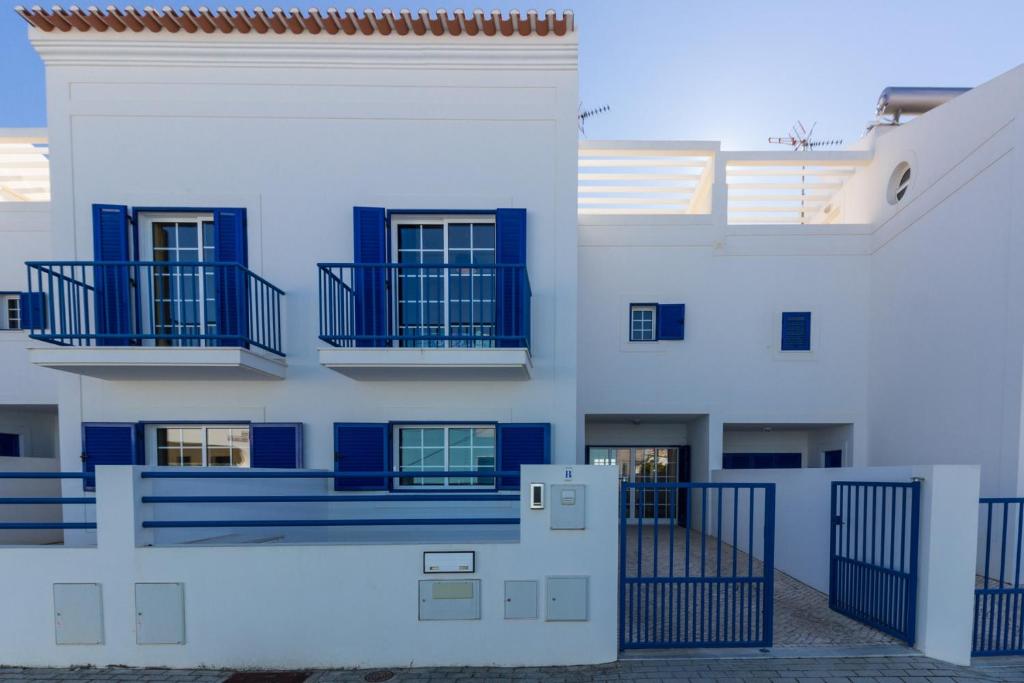 un edificio blanco con balcones azules y una puerta en Blue Villa by ALGARVEMANTA, en Manta Rota