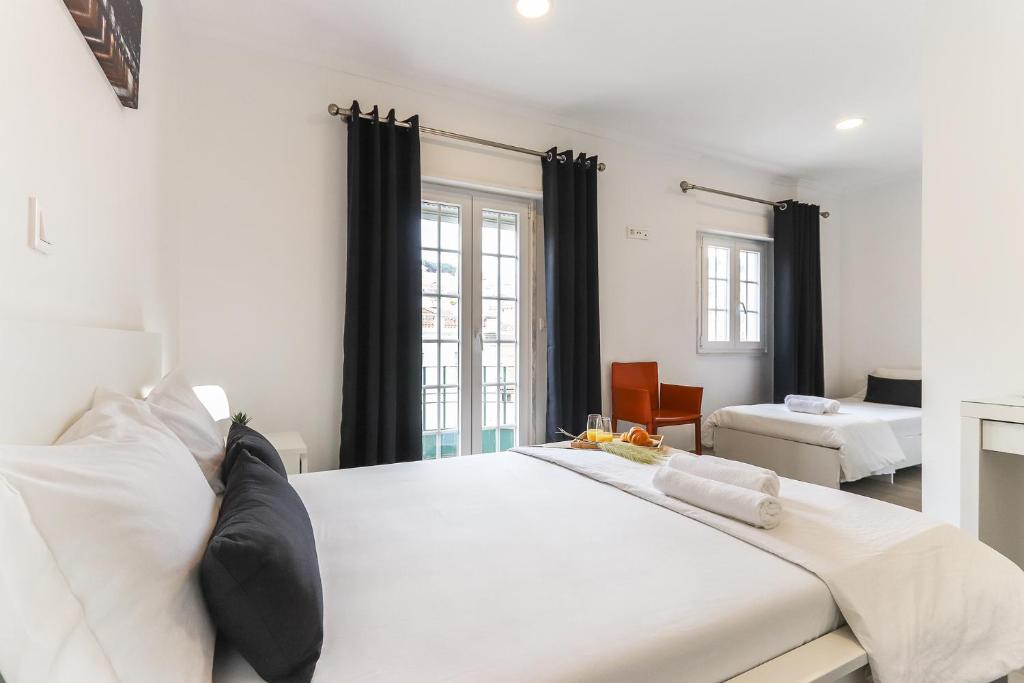 1 dormitorio con 1 cama blanca grande con cortinas negras en Downtown Lisbon Palma Suites by Homing, en Lisboa