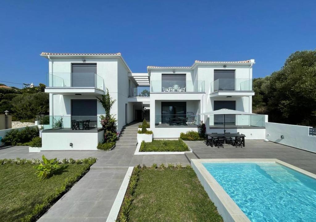 a white house with a swimming pool in front of it at Magic Kefalonia Villa in Spartia