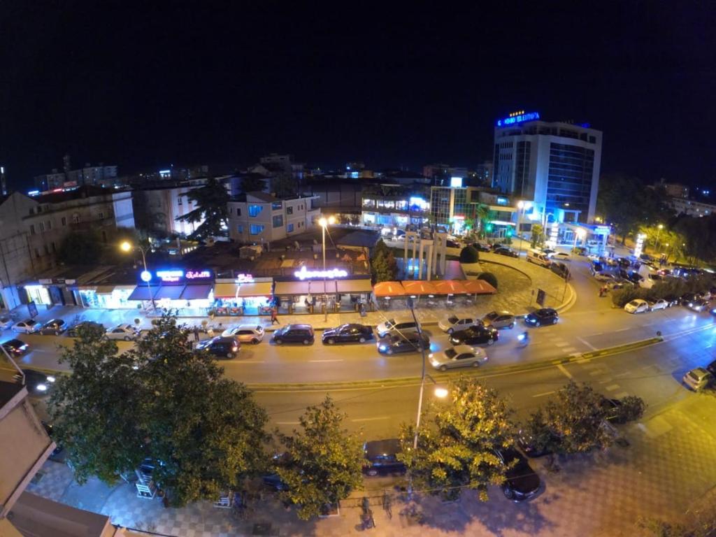 a city at night with cars parked in a parking lot at Central Hostel in Shkodër