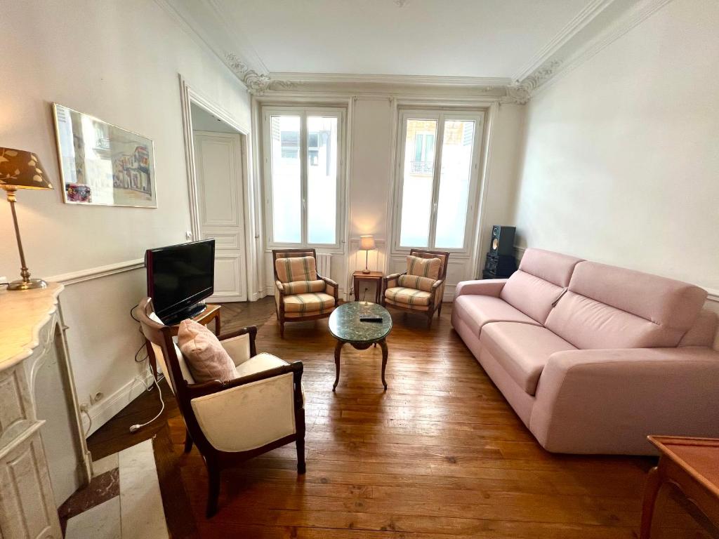 a living room with a pink couch and a tv at BASSANO in Paris