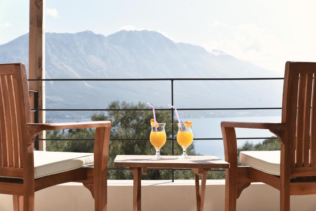 two glasses of orange juice sitting on a table on a balcony at Villa Mouria private seaview villa in Pogoniá