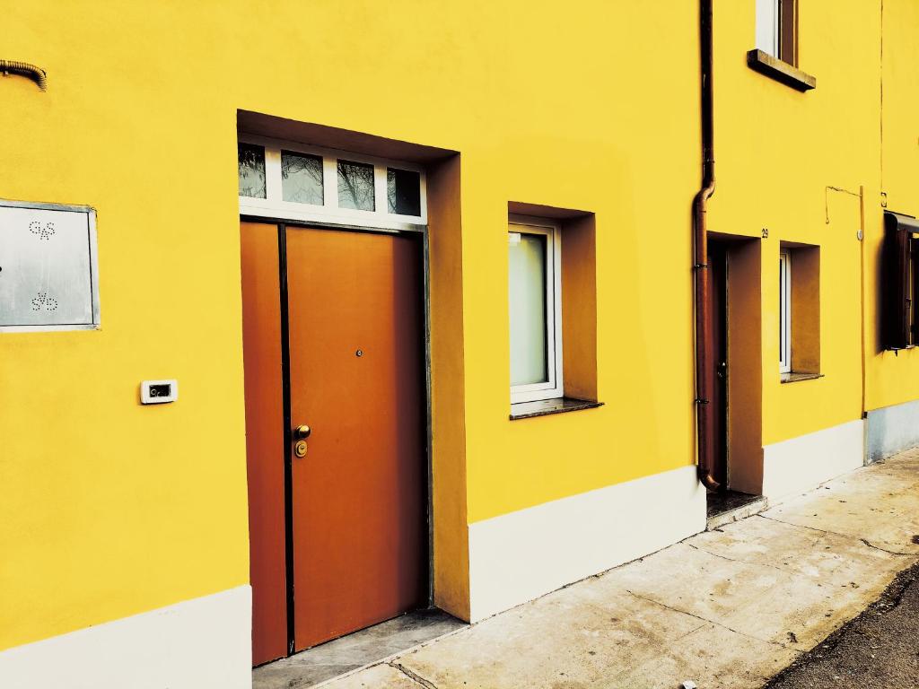 un bâtiment jaune avec une porte rouge et des fenêtres dans l'établissement Mini Cocco&Fragola, à Reggio d'Émilie