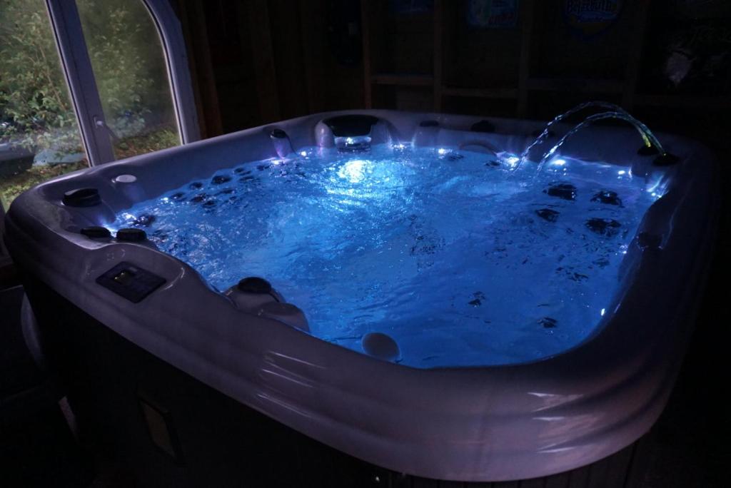 uma banheira com água azul num quarto escuro em Le cocoon em Forges-les-Eaux