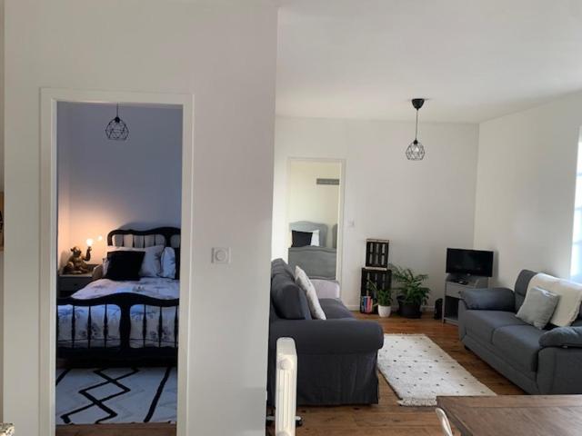 a living room with a couch and a room with a bed at Maison de l'enfant gites 