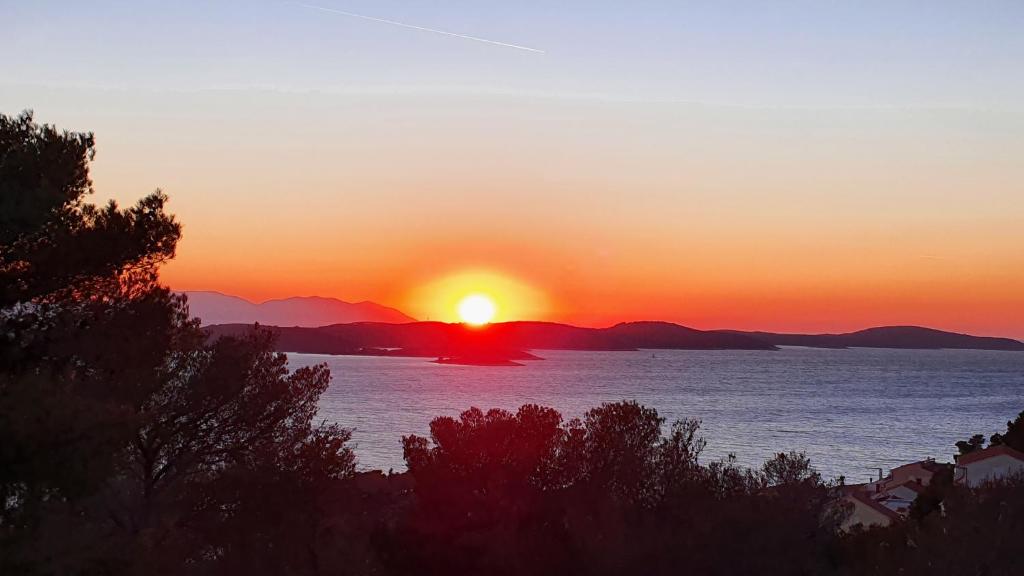 a sunset over a body of water with mountains at Apartman Filis in Hvar