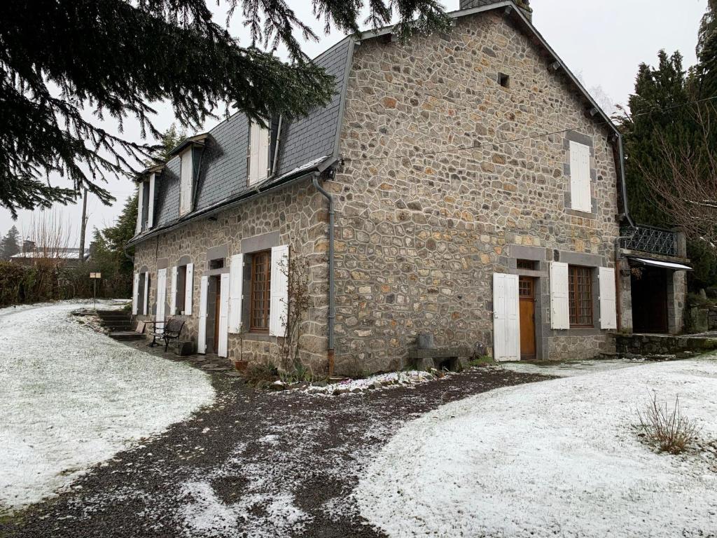 an old stone building with snow on the ground at Charmant appartement jardin/parking privé 4 personnes in La Bourboule