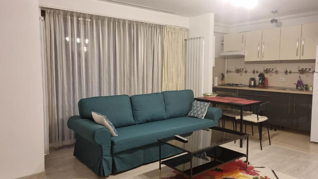 a living room with a blue couch and a kitchen at Tibiscum Apartament, Bucuresti in Bucharest