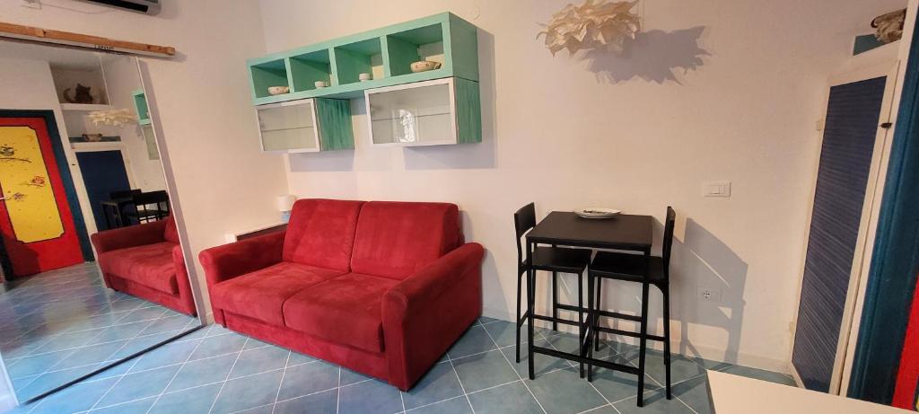 a living room with a red chair and a stool at casa arcobaleno in Isola del Giglio