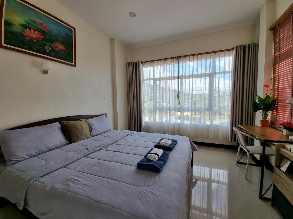 a bedroom with a bed and a desk and a window at De rae nong in Ranong