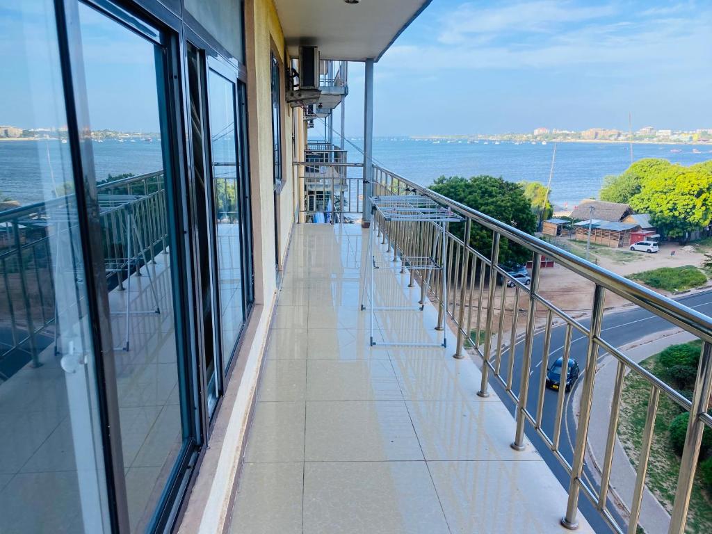 einen Balkon eines Gebäudes mit Blick auf das Wasser in der Unterkunft Masaki Anne H & Apartment in Daressalam