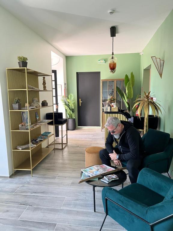 a man sitting on a couch in a living room at Hôtel Paradis in Bormes-les-Mimosas