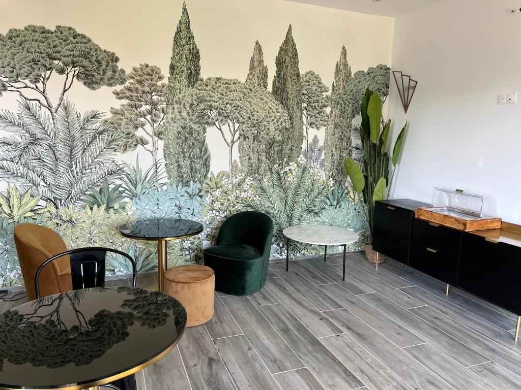 a room with tables and chairs and a wall with plants at Hôtel Paradis in Bormes-les-Mimosas