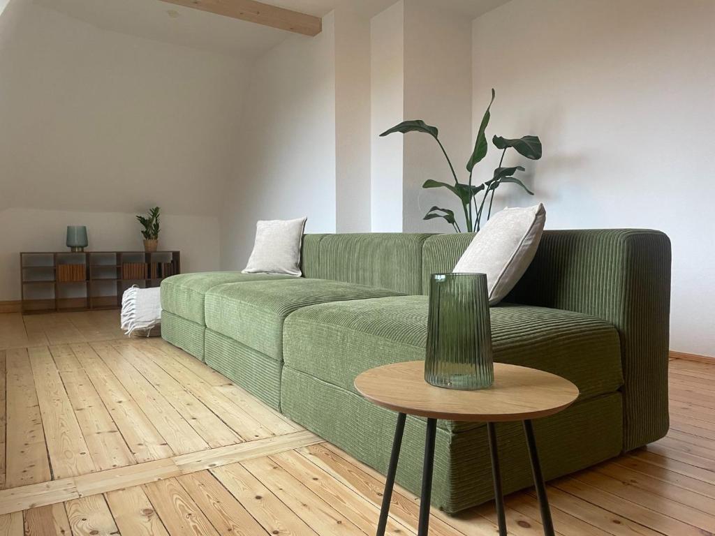 a living room with a green couch and a table at Kulturgenuss am Goethewanderweg in Weimar