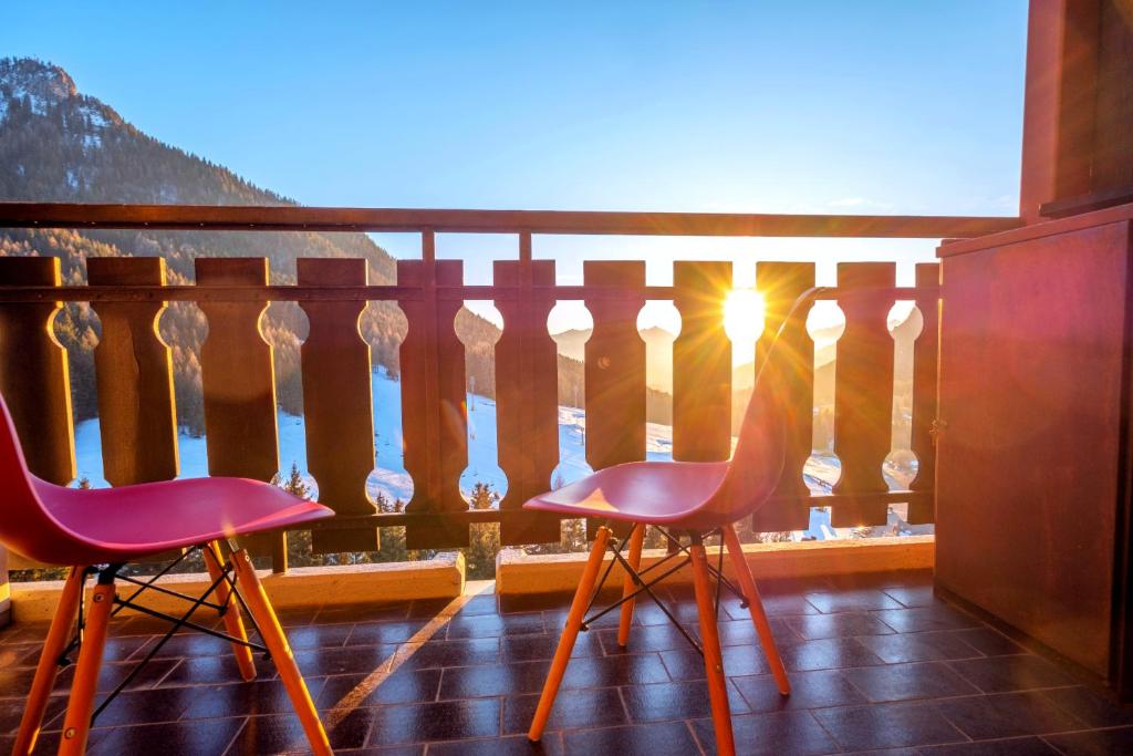 two chairs sitting on a balcony looking out at the ocean at Happy Guest Apartments - Pink Mountain Presolana in Castione della Presolana