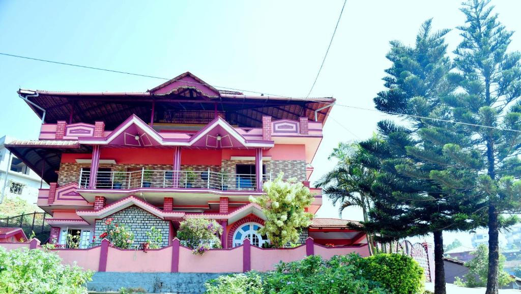 a pink building with trees in front of it at Holidayincoorg Royal Mansion in Madikeri