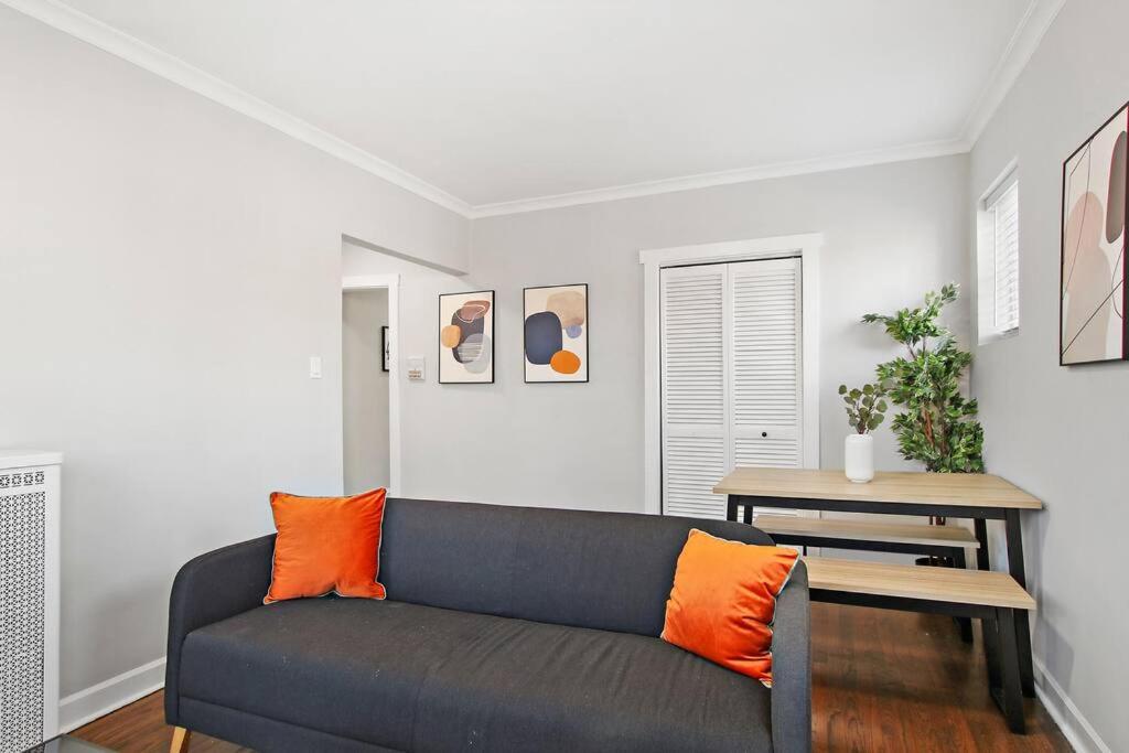 uma sala de estar com um sofá cinzento e almofadas laranja em Pleasant 2BR Apt with Furnished Kitchen - Troy 2 em Chicago