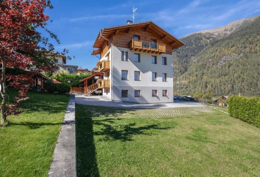 un grand bâtiment blanc avec un toit en bois dans l'établissement Appartamenti Penasa Renato, à Commezzadura