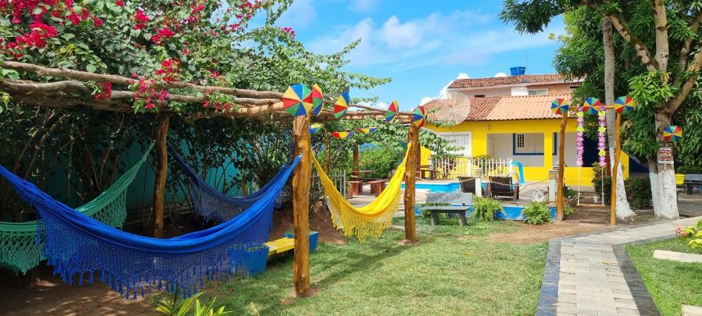 a group of hammocks in a yard with a house at Ecomar Pousada in São José da Coroa Grande