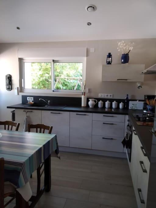a kitchen with white cabinets and a table and a window at La maison bleue in Grane