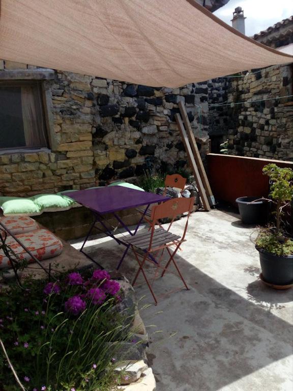 un patio avec une table et des chaises sous un parasol dans l'établissement Ruelles et terrasses, à Mirabel