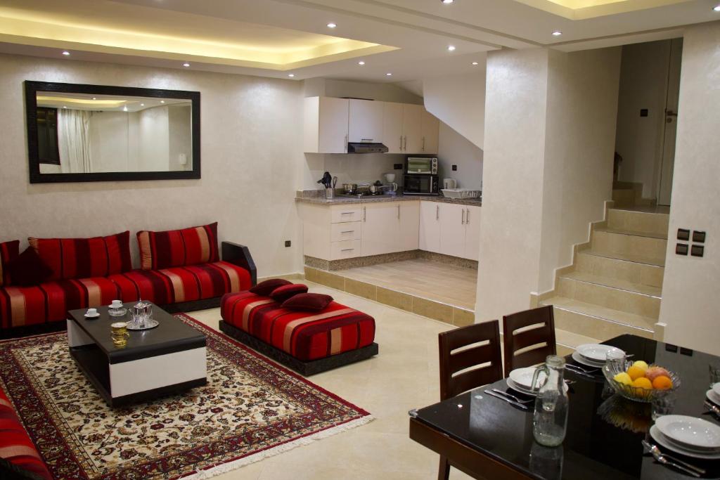 a living room with a red couch and a kitchen at Magnifique Duplex à Marrakech in Marrakesh