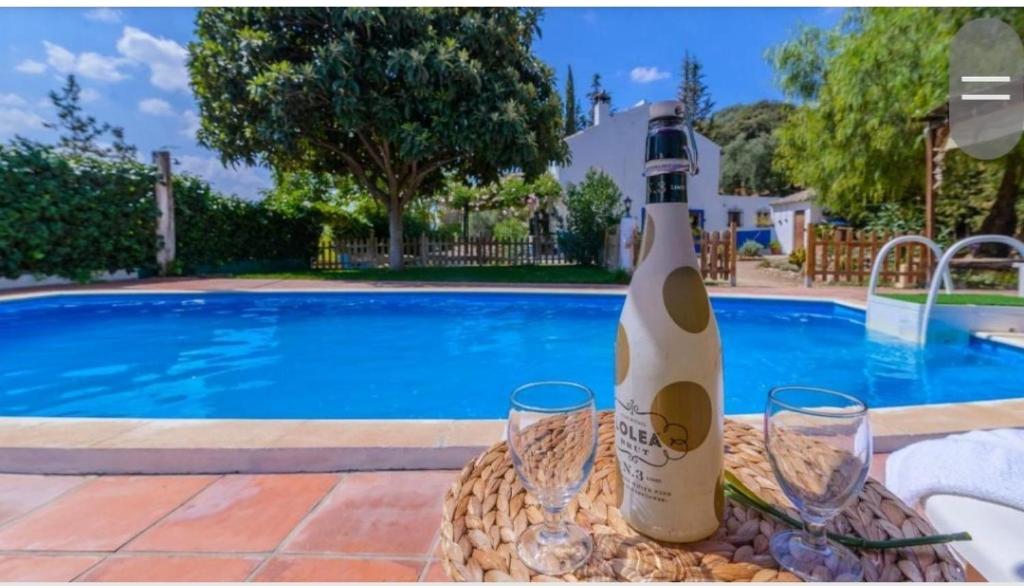una botella de vino sentada en una mesa junto a dos copas en Casa Rural la Joya en Iznájar
