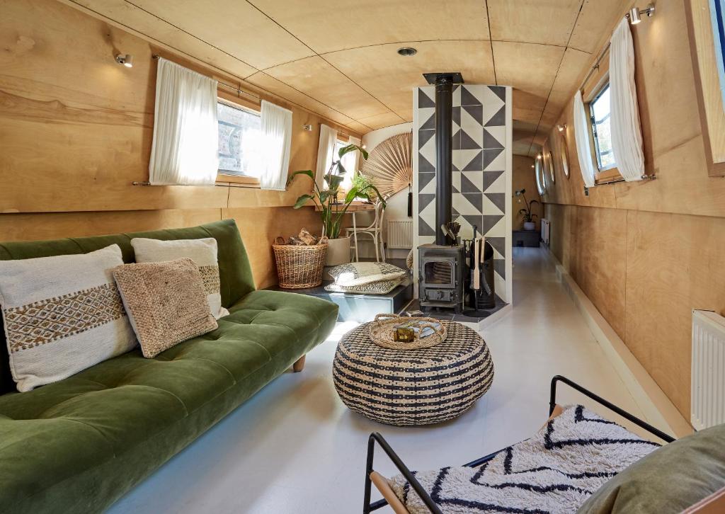 a living room with a green couch and a wood stove at Boutique Barges in London