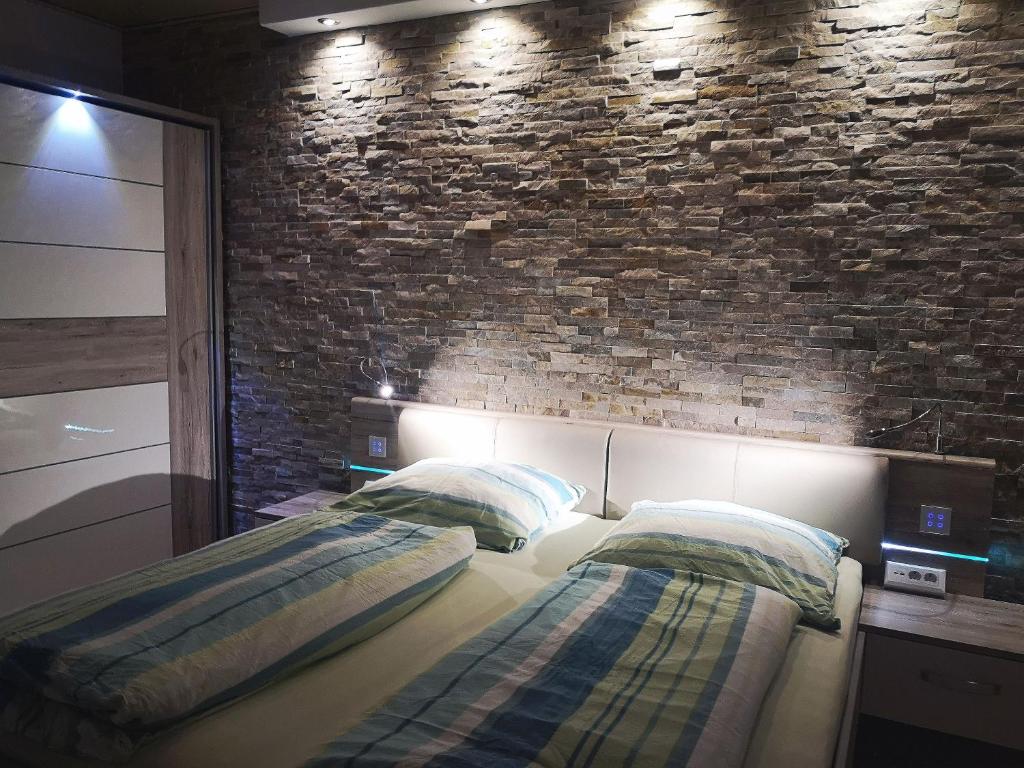 een slaapkamer met 2 bedden en een bakstenen muur bij Ferienwohnung Botschafter in Wendelstein