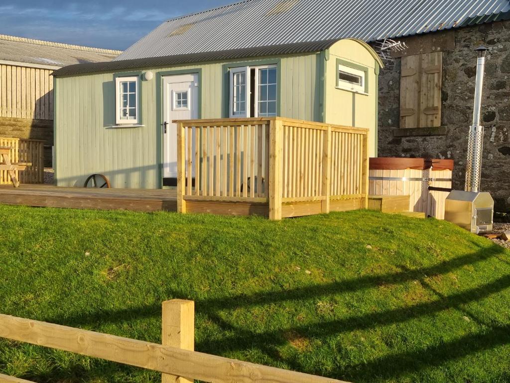 a house with a wooden fence in front of a yard at North Muasdale Farm - Byre View in Muasdale