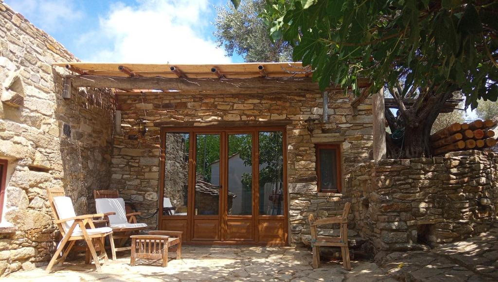 a stone house with a wooden door and chairs at The Aged Olive Tree in Raches