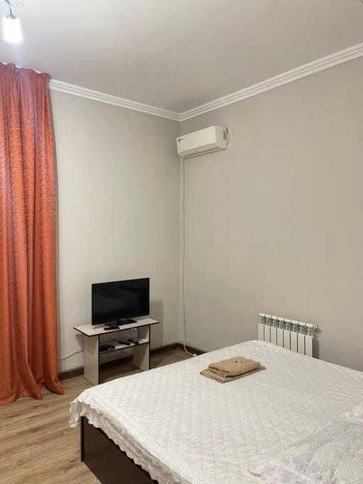 a bedroom with a bed and a tv on a table at Mondial apartments in Shymkent