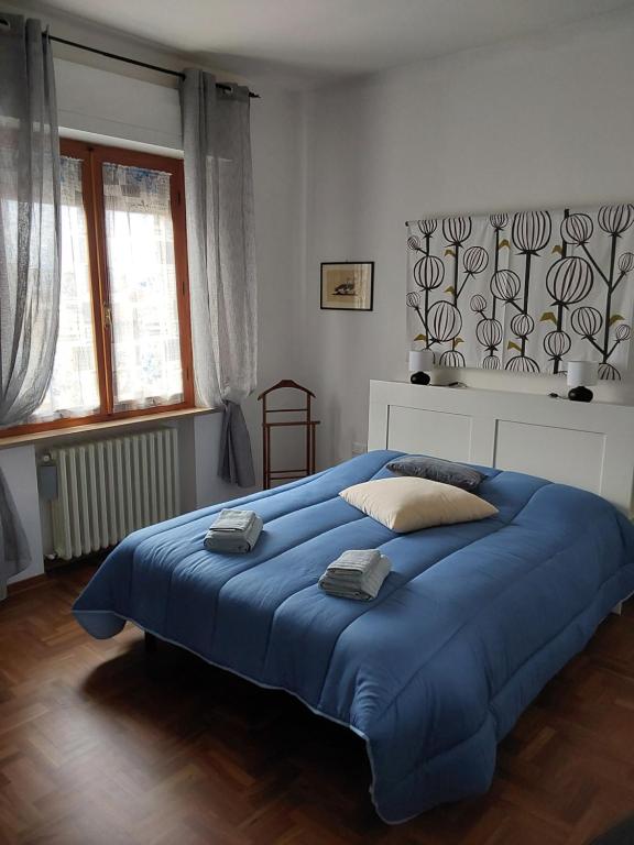 1 cama azul grande en un dormitorio blanco en La Casa di Enrico en San Quirico dʼOrcia