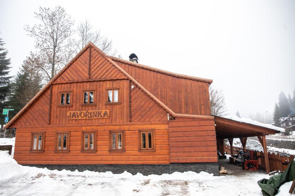 un gran edificio de madera con un cartel. en Apartmány Javořinka en Pec pod Sněžkou