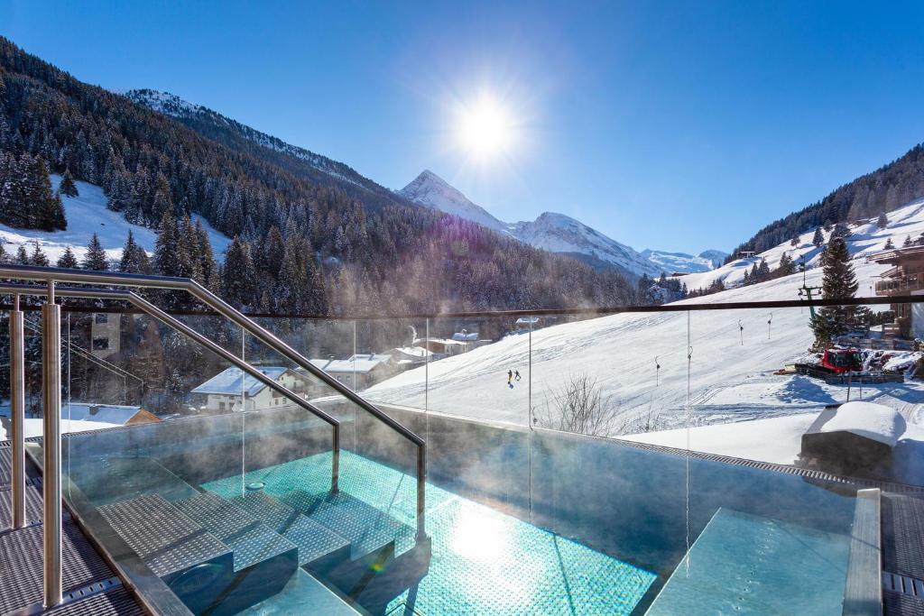 una bañera de hidromasaje en un complejo con una montaña cubierta de nieve en Hotel Jäger 3Sterne Superior, en Tux