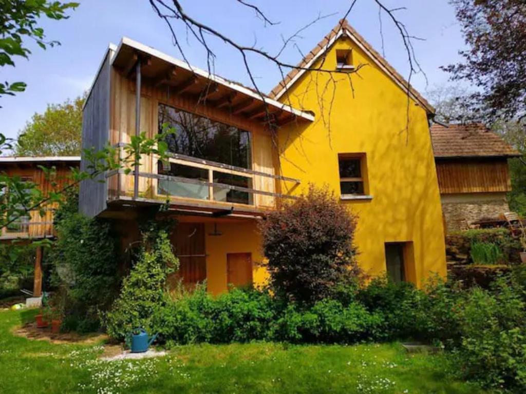 een geel huis met een balkon in een tuin bij Un havre de paix en pleine nature in Crémieu