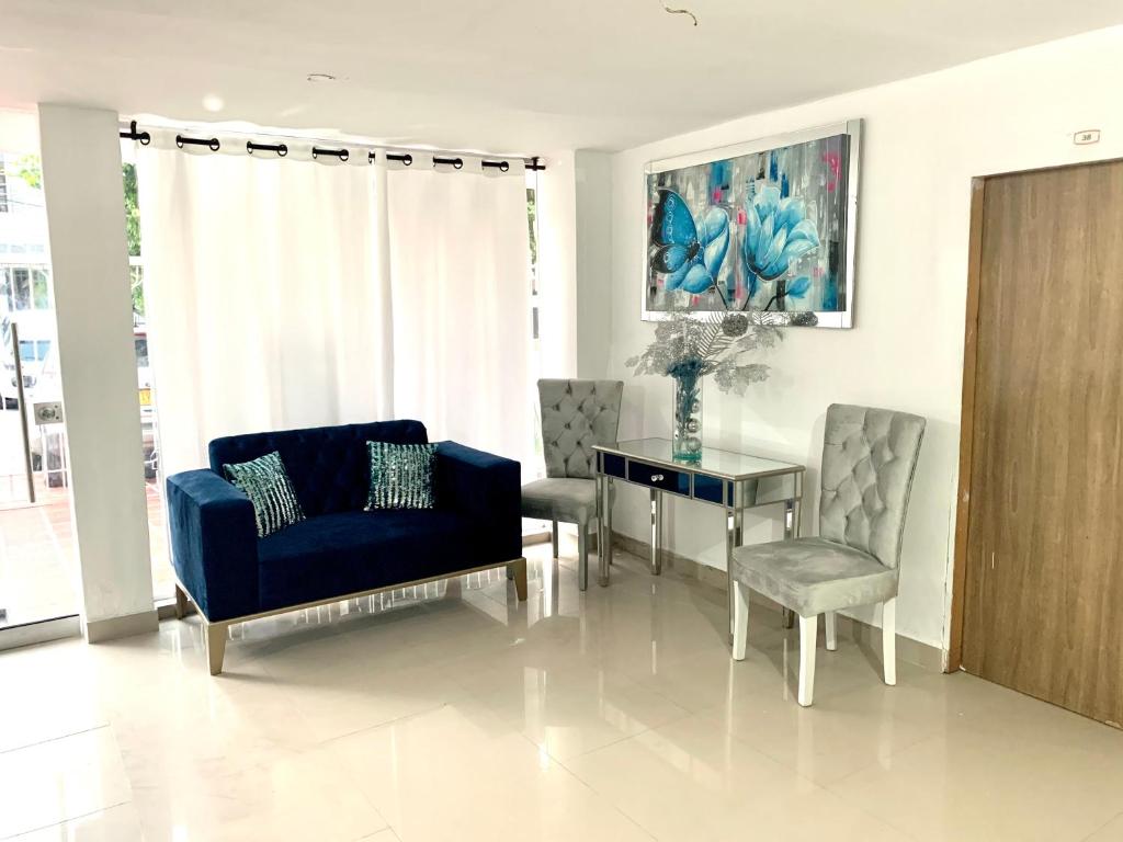 a living room with a blue couch and a table and chairs at Hostal Sabanero in Barranquilla