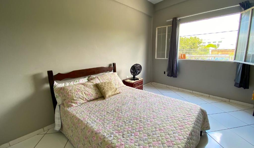 een slaapkamer met een bed en een groot raam bij Apartamento inteiro 2 quartos Wi-Fi in Montes Claros