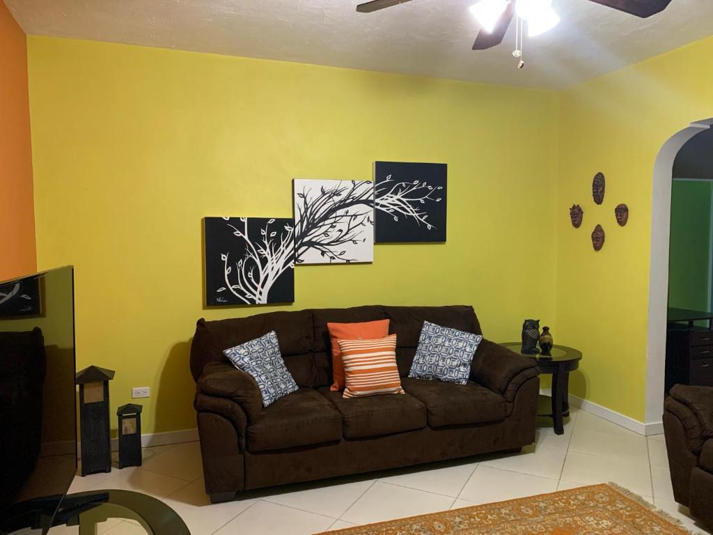 salon z brązową kanapą i żółtą ścianą w obiekcie CS Domaine Garden Villa - 2 Bedrooms w mieście Port Antonio