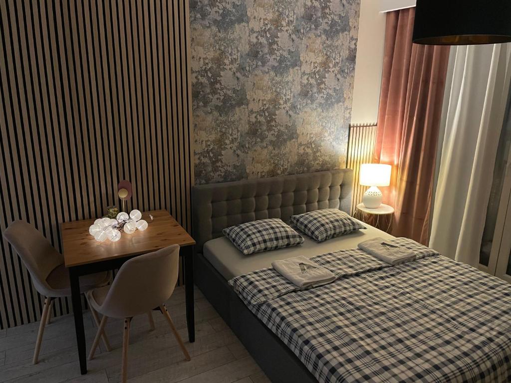 1 dormitorio con 1 cama y 1 mesa con sillas en Apartament ROYAL Chełmońskiego Śrem, en Śrem