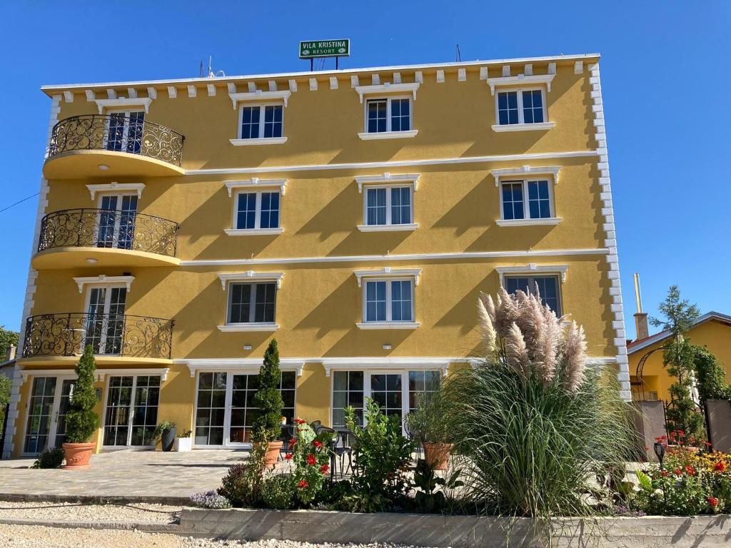 een geel gebouw met ramen en planten ervoor bij Vila Kristina in Negotin