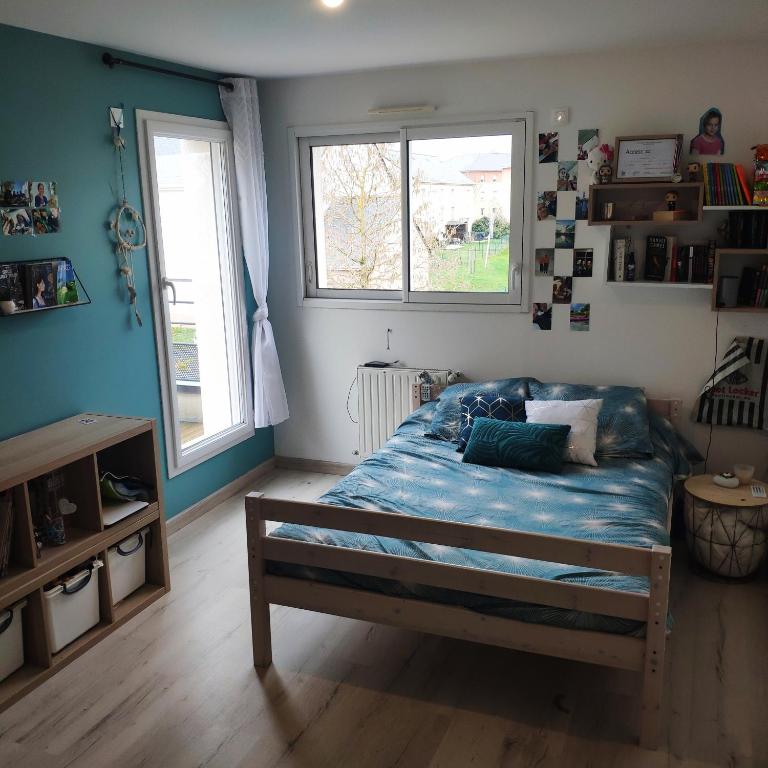 sypialnia z łóżkiem z niebieskimi prześcieradłami i oknem w obiekcie Belle chambre lumineuse w mieście Le Mans