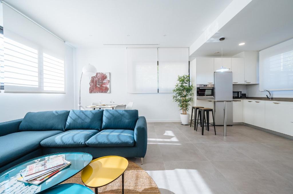 a living room with a blue couch and a kitchen at Apartmentos Marqués de Nervion in Seville